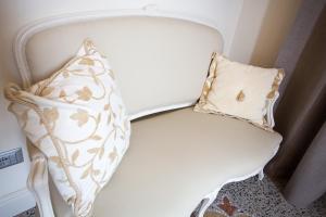 a white chair with two pillows on it at Hotel Dei Fiori Restaurant - Meeting & Spa in Alassio