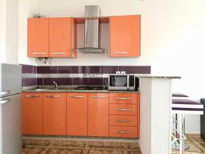 a kitchen with orange cabinets and a microwave at Appart Clim Wifi 700m de la Plage in Saïdia