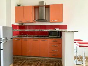 a kitchen with orange cabinets and a microwave at Appart Clim Wifi 700m de la Plage in Saïdia