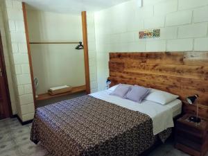 een slaapkamer met een bed met een houten hoofdeinde bij Casa Beira Rio - Sítio Terra Surya in Lumiar