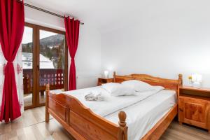 a bedroom with a bed with red curtains and a window at Pensiunea Cascada in Nemesi +11 photos