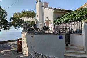 a white house with a balcony with an umbrella at Ribica Luxury Rooms in Rijeka