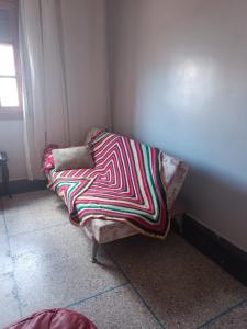 eine Couch mit einer bunten Decke auf einem Zimmer in der Unterkunft Appartement familial in Mohammedia