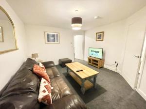 a living room with a leather couch and a coffee table at Folkestone 3 Bedroom with private parking and EV car outlet near M20 easy access to Eurotunnel, Dover & Dungeoness in Sandgate