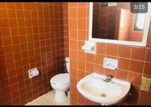 y baño con azulejos de color naranja, aseo y lavamanos. en Hotel zócalo abuelos, en Acapulco