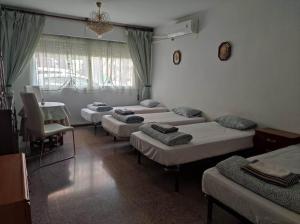un grupo de camas en una habitación con mesa y sillas en Habitacion, en Alicante