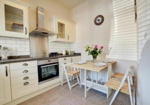 een keuken met witte kasten en een tafel met stoelen bij Marys Corner in Swanage
