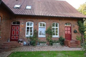 a red brick house with white windows and red doors at Altes Schulhaus in der Lüneburger Heide in Lachendorf