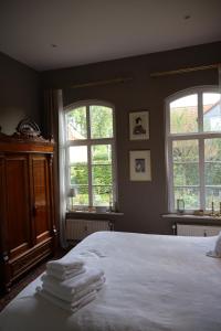 a bedroom with a large white bed with two windows at Altes Schulhaus in der Lüneburger Heide in Lachendorf
