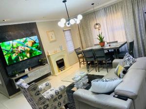 a living room with a couch and a tv and a table at Central Gabs Oasis: 2BR-Retreat in Gaborone