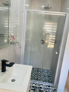 a white bathroom with a shower and a sink at Central Gabs Oasis: 2BR-Retreat in Gaborone