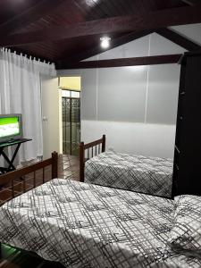 a bedroom with two beds and a flat screen tv at Hospedagem Casa da Rê in Salto