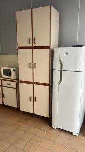 La cuisine est équipée d'un réfrigérateur blanc et d'un four micro-ondes. dans l'établissement Hospedagem Casa da Rê, à Salto