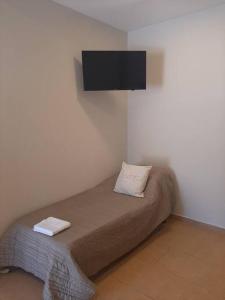 a bedroom with a bed with a tv on the wall at Temporario Necochea 2 corrientes in Corrientes