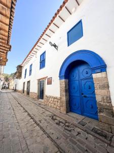 eine blaue Tür an der Seite eines weißen Gebäudes in der Unterkunft Quinta San Blas by Ananay Hotels in Cusco