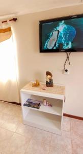 TV colgada en una pared con una mesa blanca en Los Trineos, en Ushuaia