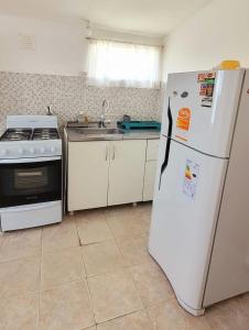 Una cocina con un refrigerador blanco y un fregadero. en Los Trineos, en Ushuaia 1 foto más