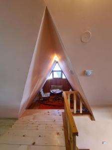 a pyramid shaped room with a staircase and a window at Vikendica Nina in Mitrovac