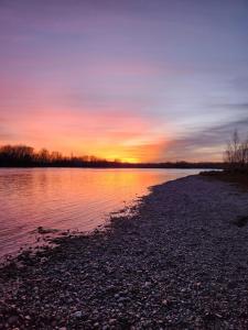 una puesta de sol en la orilla de un cuerpo de agua en El mejor descanso en Plottier