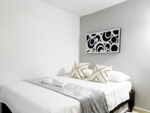 Dormitorio blanco con cama con sábanas y almohadas blancas en Aparta Hotel Downtown Guatapé, en Guatapé