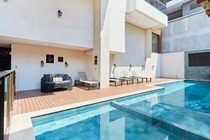 a pool with a couch and chairs next to a building at 1108 -Lindo e completo apto com piscina na Praia de Bombas in Bombinhas