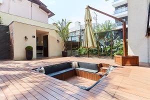 a patio with an umbrella and a couch and an empty umbrella at 1108 -Lindo e completo apto com piscina na Praia de Bombas in Bombinhas