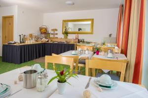 ein Restaurant mit weißen Tischen und Stühlen und einem Spiegel in der Unterkunft Hotel Leo Mühlhausen in Mühlhausen