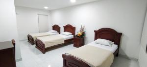 a room with three beds with white walls at Hotel Exelsior in Cúcuta