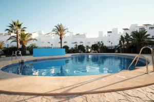 una gran piscina con palmeras y edificios en Adosado en playa Vera,3 piscinas en Vera