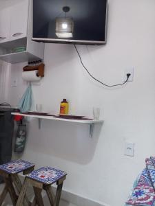 ein Fernseher, der mit zwei Hockern an einer Wand hängt in der Unterkunft Suíte confortável em Cabo Frio in Cabo Frio + 18 Fotos