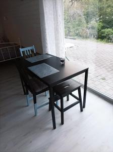 a black table and a chair in front of a window at Kleine Ferienwohnung mit Terrasse am Waldrand in Schönau