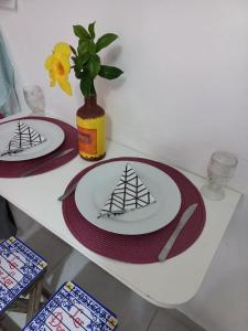 einen Tisch mit zwei Platten und eine Vase mit Blumen in der Unterkunft Suíte confortável em Cabo Frio in Cabo Frio