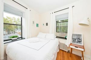 una camera bianca con un grande letto e due finestre di Three Bedroom West Village Townhouse a New York