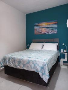 ein Schlafzimmer mit einem Bett mit einer blauen Wand in der Unterkunft Suíte confortável em Cabo Frio in Cabo Frio