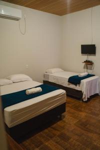 Pokój z dwoma łóżkami i telewizorem w obiekcie Pousada Capim Dourado Ponte Alta w mieście Ponte Alta do Tocantins