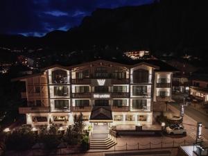un hotel di notte con una montagna sullo sfondo di The Laurin Small & Charming a Selva di Val Gardena