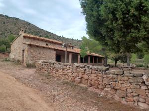 un edificio de piedra junto a una pared de piedra en La Vieja Escuela, en Fuentes de Rubielos