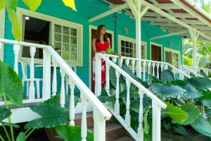 une femme debout sur la terrasse couverte avant d'une maison bleue dans l'établissement Hospedaje Yarisnori, à Bocas del Toro