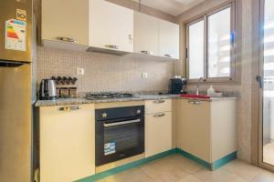 een keuken met witte kasten en een fornuis met oven bij Luxury Apartment Les perles de Marrakech in Marrakesh