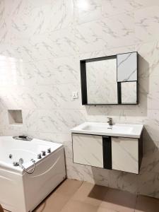 a bathroom with a tub and a sink and a mirror at Luxury Shortlet Apartment LBS, AJAH in Lagos