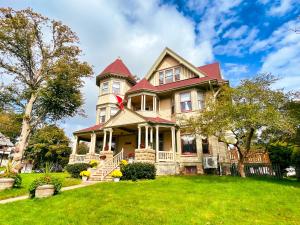 une grande maison avec un toit rouge sur une pelouse verte dans l'établissement The Eden Hall Inn, à Charlottetown