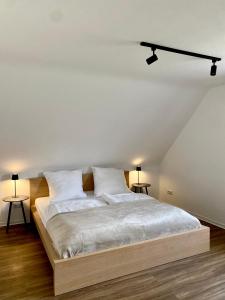 a bedroom with a bed with white sheets and two tables at Ferienwohnung am Bollrich in Goslar