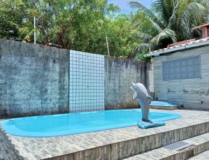 uma estátua de golfinho sentada ao lado de uma piscina em Um Paraíso no fim da rua em Barra de São Miguel