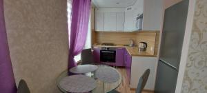 a small kitchen with a glass table and purple cabinets at Energia 2 Apartment in the city center in Narva