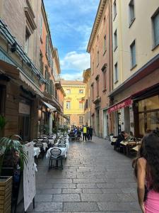 une rue avec des tables et des chaises et des personnes marchant dans la rue dans l'établissement ALBARI HOUSE, à Bologne