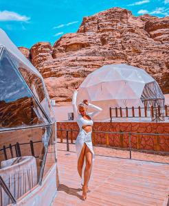 a woman in a white dress standing on a deck of a boat at Mira luxury camp in Wadi Rum