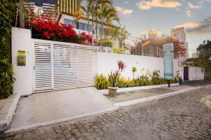 une clôture blanche avec des fleurs sur le côté d'un bâtiment dans l'établissement Pousada Flor de Ponta Negra, à Natal