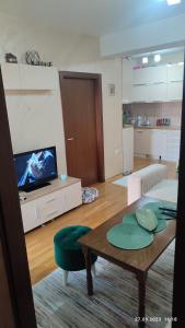 Apartments Luna Kumanovo في كومانوفو: غرفة معيشة مع طاولة وتلفزيون