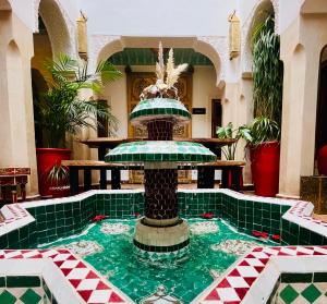 a fountain in the middle of a building with green tiles at Riad Dar Fanny in Marrakesh