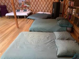 une chambre avec 3 lits dans une chambre avec une table dans l'établissement Yourte proche canal, à Saffré